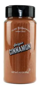 A clear plastic jar with a black lid containing Olde Thompson Saigon Cinnamon spice. The label features Saigon Cinnamon in bold letters, with the net weight of 4.2 oz (119g) displayed at the bottom.