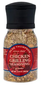 A bottle of Olde Thompson Chicken Grilling Seasoning with a grinder top. The red label shows herbs and spices inside, marked since 1944. The net weight is 3.75 oz (106.3g). The label mentions its disposable and recyclable.