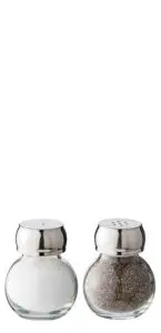 A clear glass salt shaker filled with white salt is next to a similar shaker filled with ground black pepper. Both have metallic tops with holes for dispensing.