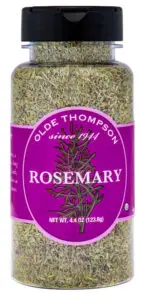 A clear plastic jar with a black lid contains dried rosemary. The label is purple with the text Olde Thompson and Rosemary along with an illustration of a rosemary sprig. The net weight is 4.4 oz (123.8g).