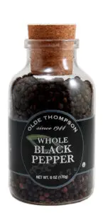 A clear glass jar with a cork lid, containing whole black peppercorns. The label reads Olde Thompson since 1944, Whole Black Pepper. The jars capacity is 6 oz (170g).