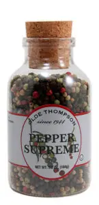 A clear glass jar with a cork lid containing a mix of peppercorns. The label reads Olde Thompson since 1944 Pepper Supreme. The jars net weight is 5.8 oz (164g).