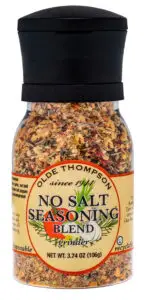 A bottle of Olde Thompson No Salt Seasoning Blend, featuring a grinder top. The label shows assorted spices like dried carrots and onions. It notes the product is recyclable, net weight 3.74 oz (106g).