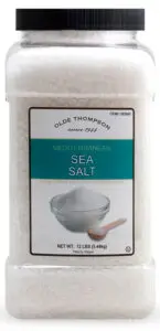 A large plastic container of Olde Thompson Mediterranean Sea Salt, labeled as 12 lbs (5.44 kg). The label features an image of a bowl filled with salt and states that the salt does not supply iodide, a necessary nutrient.