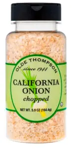 A plastic jar of Olde Thompson chopped California onion, weighing 5.9 oz (164.4g). The label is green with black and dark green text and features a vintage design, with the brands founding year, 1944, mentioned.