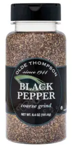 A transparent plastic bottle of Olde Thompson Black Pepper with a coarse grind, weighing 6.4 ounces (181.4 grams). The label is black with white text and includes a design of a green leaf. The cap is black.