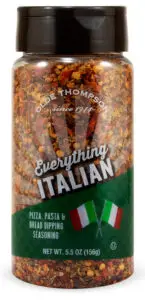 A container of Olde Thompson Everything Italian seasoning, featuring red and green spices. The label shows Italian flags and mentions its for pizza, pasta, and bread dipping. Net weight is 5.5 oz (156g).