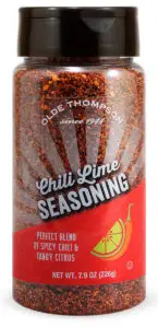 A clear plastic jar of Olde Thompson Chili Lime Seasoning. The label features an illustration of a lime wedge and chili pepper, with text stating Perfect Blend of Spicy Chili & Tangy Citrus. Net weight is 7.9 oz (226g).