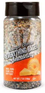 A plastic bottle of Olde Thompson Asiago Cheese Everything Bagel Seasoning. The label shows garlic, onion, sesame seeds, and poppy seeds. The net weight is 7 oz (198g).