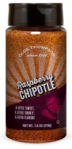 A spice bottle labeled Olde Thompson Raspberry Chipotle with a description: A little sweet, a little smoky; a lotta flavor! The bottle has a reddish-brown seasoning visible through it and weighs 7.6 oz (218g).