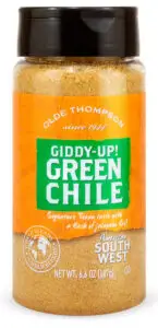 A 6.6 oz jar of Olde Thompsons Giddy-Up! Green Chile seasoning blend. The label is orange with green and white text, advertising Signature Texan taste with a flash of jalapeño fire! and American South West flavors.