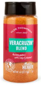 A bottle of Olde Thompson Veracruzin Blend spice. The label is pink and turquoise with text describing it as having garlicky goodness with a zing of jalapeños. The bottle contains 6.1 oz (173g).