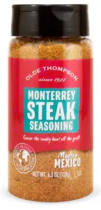 A bottle of Olde Thompson Monterrey Steak Seasoning. The label is red with turquoise and white text, and it has decorative elements like since 1941 and Modern Mexico. The net weight is 6.3 oz (179g).