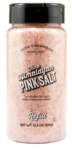 A transparent plastic bottle labeled Olde Thompson Fine Himalayan Pink Salt Refill. The bottle contains pink salt and has a black cap. It states, This salt does not supply iodide, a necessary nutrient. Net weight: 12.5 oz (354g).