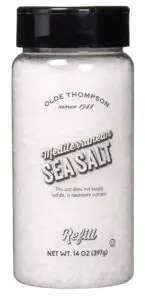 A clear bottle with a black cap labeled Olde Thompson Mediterranean Sea Salt. The text indicates its a refill net weight of 14 oz (397g), and notes that the salt does not supply iodide.