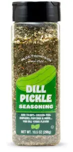 A clear plastic bottle with a black lid containing dill pickle seasoning. The label features a vibrant green pickle illustration and suggests using it for dips, chicken, fish, burgers, popcorn, and more. Net weight: 10.5 oz (298g).